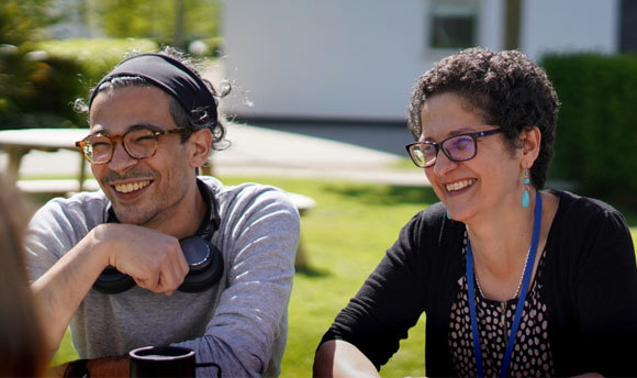 Two people sitting outdoors in the sunshine on the QMU campus